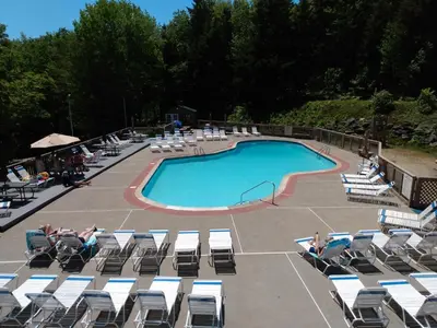 a swimming pool with chairs and people sitting around it at Mountain Retreat in Wilmington