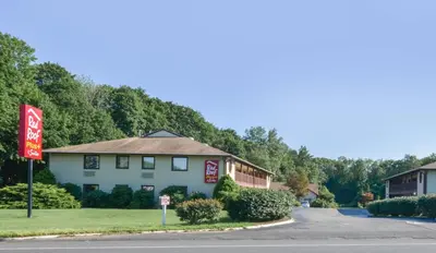 a building with a sign on the side of a road at Red Roof Inn PLUS+ & Suites Guilford in Guilford