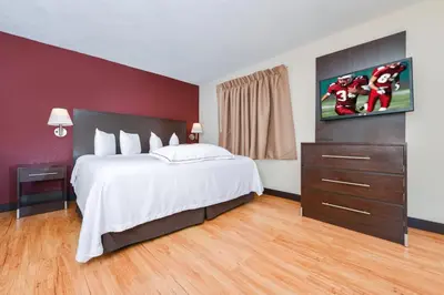a bedroom with a large white bed and a red wall at Red Roof Inn PLUS+ & Suites Guilford in Guilford