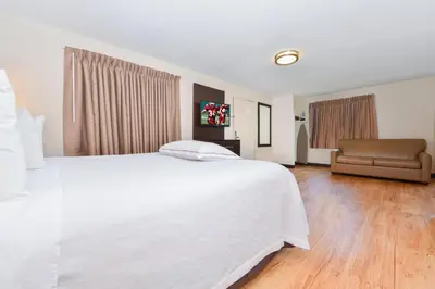 a bedroom with a large white bed and a couch at Red Roof Inn PLUS+ & Suites Guilford in Guilford