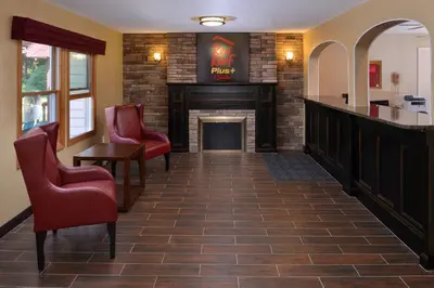 a waiting room with chairs and a fireplace at Red Roof Inn PLUS+ & Suites Guilford in Guilford