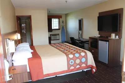 a hotel room with a bed and a flat screen tv at American Inn in Branford