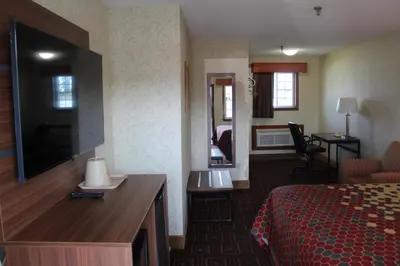 a hotel room with a bed and a flat screen tv at American Inn in Branford