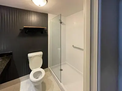 a bathroom with a toilet and a glass shower at The Century House Latham - North Albany, an Ascend Collection Hotel in Latham