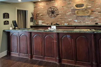 a kitchen with a wooden counter with a brick wall at The Century House Latham - North Albany, an Ascend Collection Hotel in Latham