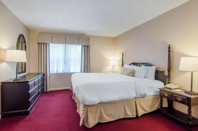 a hotel room with a large bed and two lamps at The Century House Latham - North Albany, an Ascend Collection Hotel in Latham