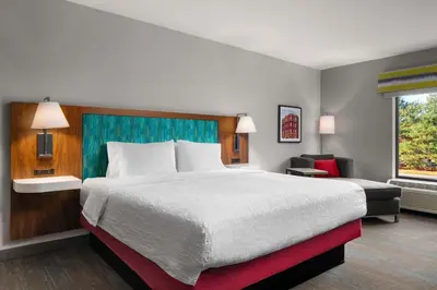 a hotel room with a large bed and a chair at Hampton Inn Chicopee - Springfield in Chicopee