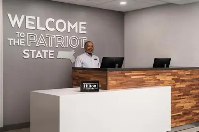 a man standing at a reception desk in a office at Hampton Inn Chicopee - Springfield in Chicopee