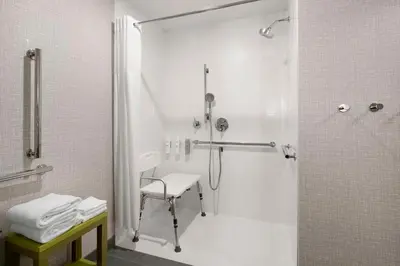 a bathroom with a shower and a chair in it at Hampton Inn Chicopee - Springfield in Chicopee
