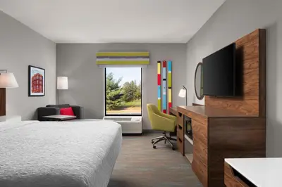a hotel room with a bed and a flat screen tv at Hampton Inn Chicopee - Springfield in Chicopee