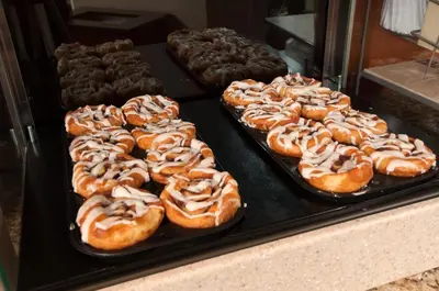 a bunch of donuts on trays in a display case at Holiday Inn Express Vernon-Manchester by IHG in Vernon