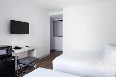 a hotel room with a bed and a desk with a tv at The Gatsby Hotel in New York