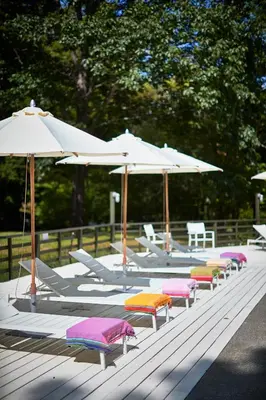 a row of lounge chairs with umbrellas on a deck at Troutbeck in Amenia