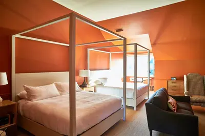 a bedroom with a canopy bed with an orange wall at Troutbeck in Amenia
