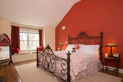 a bedroom with a large bed with orange walls at Caldwell House Bed and Breakfast in Salisbury Mills