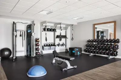 a room with a gym with a bench and weights at Hampton Inn & Suites West Haven in West Haven