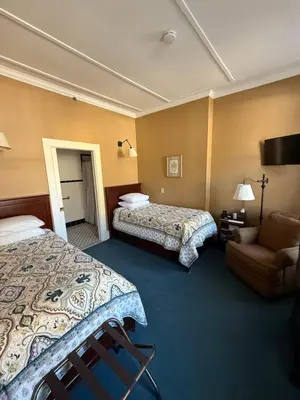 a hotel room with two beds and a couch at The Inn at Cooperstown in Cooperstown