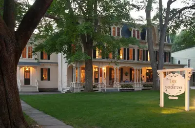 a large white house with a sign in front of it at The Inn at Cooperstown in Cooperstown