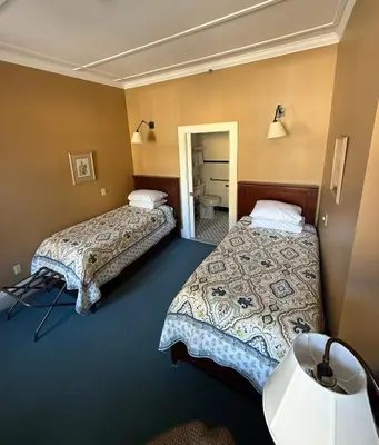 a hotel room with two beds and a bathroom at The Inn at Cooperstown in Cooperstown