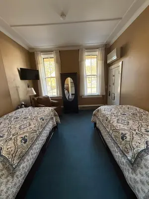 a hotel room with two beds and a mirror at The Inn at Cooperstown in Cooperstown