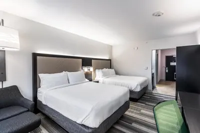 a hotel room with two beds and a couch at Holiday Inn Express & Suites Jersey City North - Hoboken by IHG in Jersey City