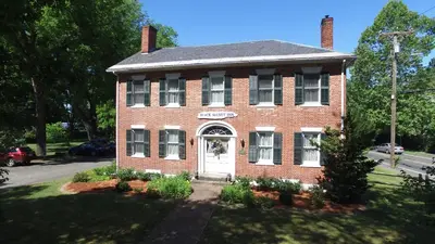 an old red brick house with a white door at The Black Walnut Inn in Amherst