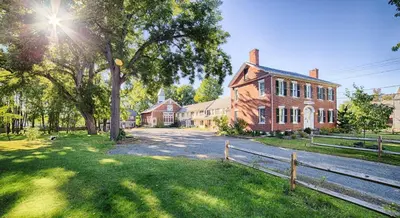 an old brick house with a fence in front of it at The Black Walnut Inn in Amherst