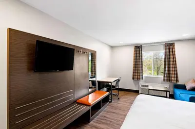 a hotel room with a bed and a flat screen tv at Econo Lodge Bethel - Danbury in Bethel