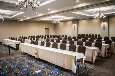a conference room with rows of tables and chairs at Holiday Inn Express & Suites - Albany Airport - Wolf Road by IHG in Albany