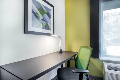 a room with a desk and a green chair at Holiday Inn Express & Suites - Albany Airport - Wolf Road by IHG in Albany