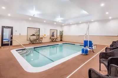 a swimming pool in a room with chairs and tables at Holiday Inn Express & Suites - Albany Airport - Wolf Road by IHG in Albany