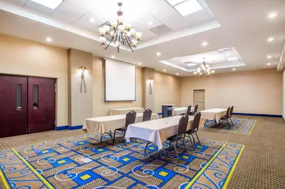 a conference room with tables and chairs and a projection screen at Holiday Inn Express & Suites - Albany Airport - Wolf Road by IHG in Albany