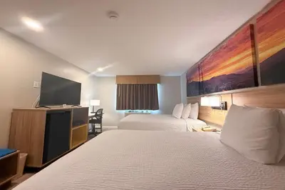a hotel room with two beds and a flat screen tv at Days Inn by Wyndham Torrington in Torrington