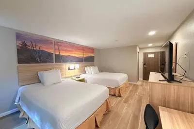 a hotel room with two beds and a flat screen tv at Days Inn by Wyndham Torrington in Torrington