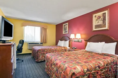 a hotel room with two beds and a flat screen tv at Days Inn by Wyndham Torrington in Torrington