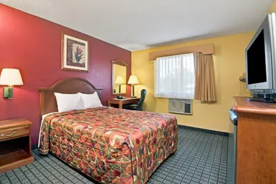 a hotel room with a bed and a flat screen tv at Days Inn by Wyndham Torrington in Torrington