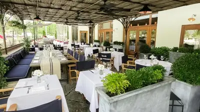 a restaurant with white tables and chairs and plants at Delamar Greenwich Harbor in Greenwich