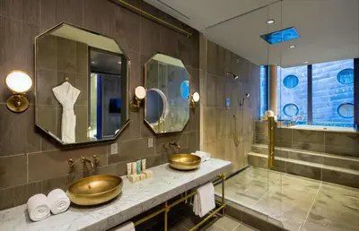 a bathroom with two gold sinks and a shower at Dream Downtown, by Hyatt in New York