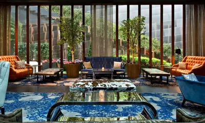 a lobby with chairs and tables and a large window at Dream Downtown, by Hyatt in New York