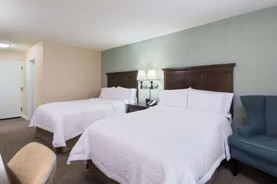 a hotel room with two beds and a blue chair at Hampton Inn White Plains/Tarrytown in Elmsford