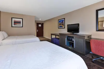 a hotel room with two beds and a flat screen tv at Hampton Inn Waterbury in Waterbury