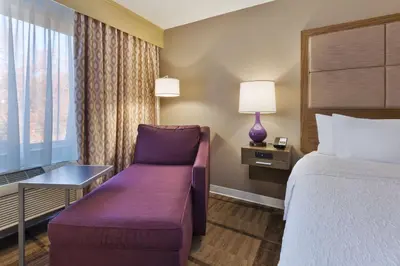 a hotel room with a bed and a couch and a window at Hampton Inn Waterbury in Waterbury
