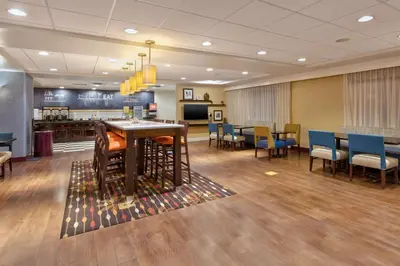 a waiting room with chairs and a table and a bar at Hampton Inn Waterbury in Waterbury