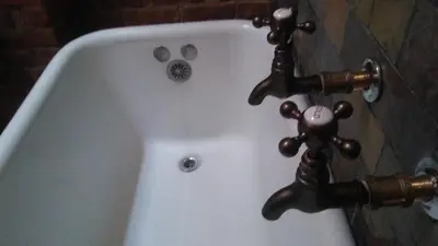 a white bath tub with two faucets on it at The Harlem Flophouse in New York