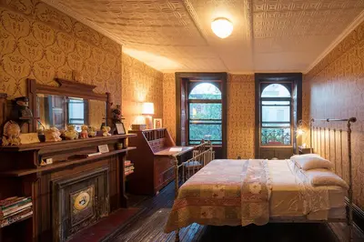 a bedroom with a bed and a desk and windows at The Harlem Flophouse in New York