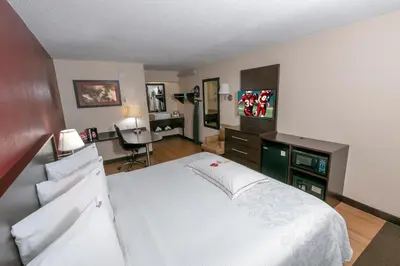 a bedroom with a large white bed and a desk at Red Roof Inn PLUS+ West Springfield in Springfield