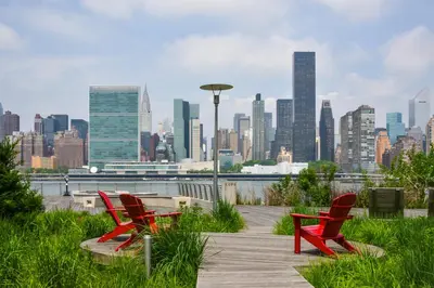 two red chairs on a boardwalk with a view of a city at Z NYC Hotel in Queens