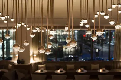 a dining room with tables and chairs and lights at AC Hotel by Marriott New York Downtown in New York