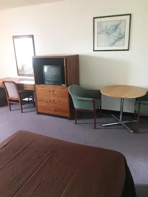 a hotel room with a tv and a table and chairs at Village Motel in Ellenville