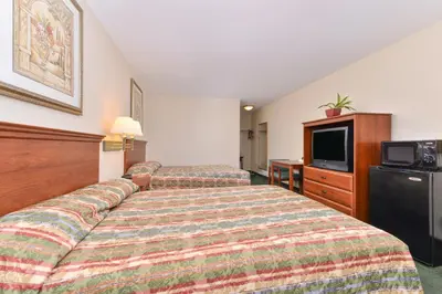 a hotel room with two beds and a tv at Tower Inn and Suites of Guilford / Madison in Guilford